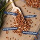 Ein Holzlöffel mit braunen Erdnüssen auf Jute, umgeben von verstreuten Erdnüssen, beschriftet mit 'fetthaltig', 'nahrhaft', 'energiespendend', 'mineralstoffreich'.