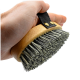 Eine Hand hält eine Haustierpflegebürste mit einem Holzgriff und schwarzen Borsten, mit einem schwarzen Riemen für besseren Halt.