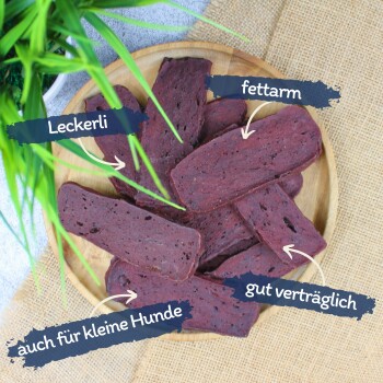 Ein Holzbrett hält Haustierleckerlis, beschriftet auf Deutsch: "schmackhaft", "Proteinquelle", "fettarm" und "leicht verdaulich."