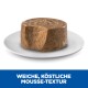 Ein runder, mousse-artiger Tiernahrung auf einem weißen Teller, mit "WEICHE, KÖSTLICHE MOUSSE-TEXTUR" in fettem Weiß auf blauem Hintergrund.