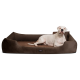 Ein weißer Hund, der bequem auf einem braunen Hundebett mit erhöhten Rändern liegt, das ein gemütliches Design zeigt.