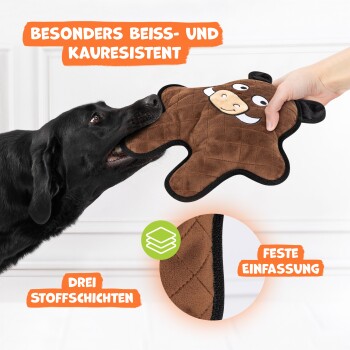 Ein schwarzer Hund, der verspielt an einem braunen, bärenförmigen Kauspielzeug zieht, mit dem Text "Besonders beiss- und kaureresistent" und "Drei Stoffschichten."