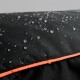 Nahaufnahme eines schwarzen, wasserdichten Haustierbettes mit Wassertropfen auf der Oberfläche, mit einem leuchtend orangefarbenen Rand.