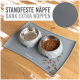 Graue Haustierfütterungsmatte mit zwei geometrischen Schüsseln, eine leer und eine mit Trockenfutter gefüllt, mit dem Text 'STANDFESTE NÄPFE DANK EXTRA NOPPEN.'