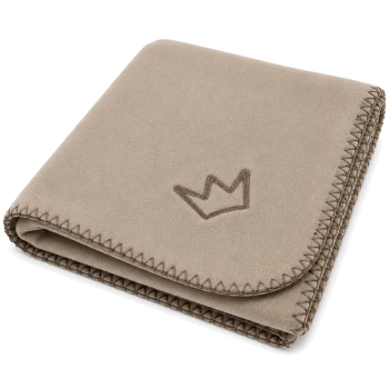 Gefaltete beige, wildlederähnliche Hundedecke mit aufgesticktem Kronenlogo und Zickzack‑Whipstich‑Kante.