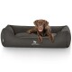 Ein brauner Hund, der auf einem gemütlichen, dunkelgrauen Haustierbett mit dem Logo 'KNUFFELWUFF' sichtbar auf der Vorderseite entspannt.