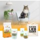 Eine Maine Coon Katze sitzt auf einem weißen Stuhl mit Haustierprodukten: Hundefutter, ein grünes Supplement, Gesundheitsgläser und eine Tragetasche.