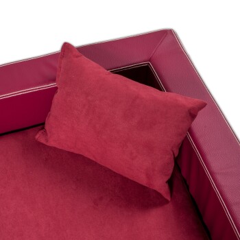 Rotes Haustierbett mit einem plüschigen Kissen, das eine strukturierte Oberfläche und einen kontrastierenden Rand aufweist, vor einem schwarzen Hintergrund.