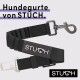 Schwarzes Hundesicherheitsgeschirr von STUCH, mit einem stabilen Clip und einem Markenlabel. Der Text lautet "Hundegurte von STUCH."