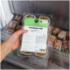 Hand hält gefrorene Hundefutterpackung 'Komplett-Mix Lamm' im Gefrierschrank, grünes Etikett und Barcode sichtbar