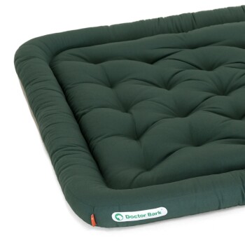 Grünes Haustierbett mit gepolstertem Design und einem gepolsterten Rand, mit dem Logo "Doctor Bark" an der Seite.