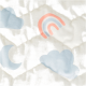 Gros plan d'un tissu doux et matelassé présentant un design ludique avec des nuages bleu clair, une lune croissante et un arc-en-ciel pastel.