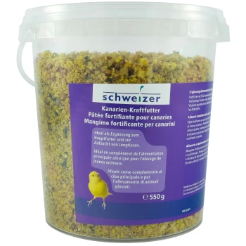 Un conteneur en plastique transparent de nourriture pour canaris étiqueté "schweizer Kanarien-Kraftfutter," contenant un mélange jaune et brun, 550g.