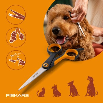 Fiskars-Tierpflegescheren vor orangefarbenem Hintergrund mit Person, die das Gesicht eines lockigen braunen Hundes trimmt, 'FISKARS'-Logo.
