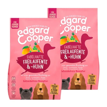 Zwei Tüten Edgard Cooper getreidefreies Hundefutter für Junghunde, mit einem rosa Hintergrund und Illustrationen von Gemüse und einer Ente.