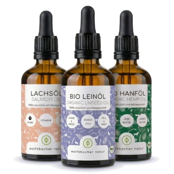 Drei Flaschen Haustieröle: Bio-Leinöl, Lachsöl und Bio-Hanföl, jede mit bunten Etiketten, die Vorteile und Inhaltsstoffe detailliert beschreiben.