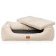 Brauner Hund schläft in einem beigen Cord-Hundebett mit kleinem Leder-Logoetikett im Wohnzimmer mit Sofa und Topfpflanzen.