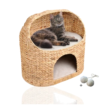 Ein gemütliches, gewebtes Katzenbett mit einer getigerten Katze, die darauf liegt, ausgestattet mit einem weichen Kissen und einem Eingang darunter, begleitet von zwei Spielbällen.