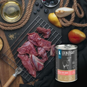 Dose LIEBESGUT-Hundefutter mit der Aufschrift 'Hirsch für Hunde' neben rohem Hirschfleisch auf einem Abkühlgitter mit Birnen, Beeren und Öl.