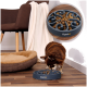 Ein kleiner brauner Hund frisst aus einer blauen langsamen Futter-Schüssel mit Wirbel-Design, die auf einem Holzboden neben einem Hundebett und einem Stuhl steht.