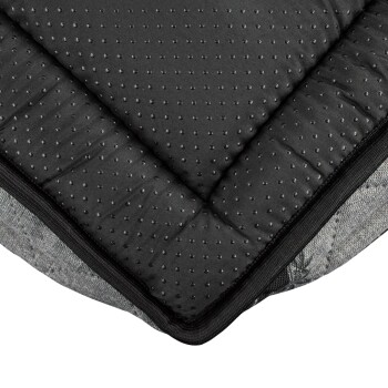 Nahaufnahme eines Haustierbettes mit einer strukturierten schwarzen Oberfläche mit kleinen Punkten und einem grauen gemusterten Rand, das seinen Komfort und sein Design hervorhebt.