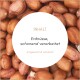 Nahaufnahme von rohen Erdnüssen mit einem weißen Kreis, der deutschen Text enthält: "INHALT Erdnüsse, schonend verarbeitet artgerecht & natürlich".