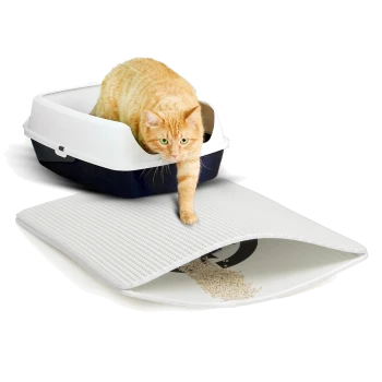 Eine ingwerfarbene Katze tritt aus einer weißen und marineblauen Katzentoilette, mit einem strukturierten weißen Teppich darunter, auf dem Streu verstreut ist.