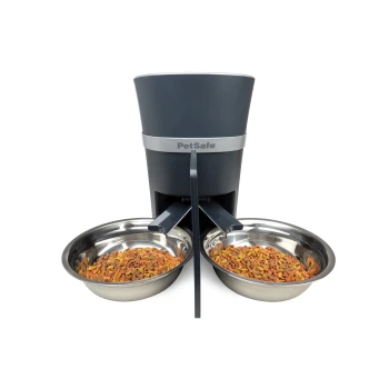 Futterteiler mit Schüssel für 2 Haustiere PetSafe automatischer Futterspender mit zwei Edelstahlschalen, gefüllt mit buntem Trockenfutter, entworfen für eine bequeme Fütterung.