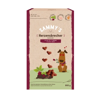 Ein Hundecartoon mit einem Herzkragen steht neben herzförmigen Leckereien auf einer Tüte mit der Aufschrift "SAMMY'S Herzensbrecher" mit Rote Beete und Löwenzahn.