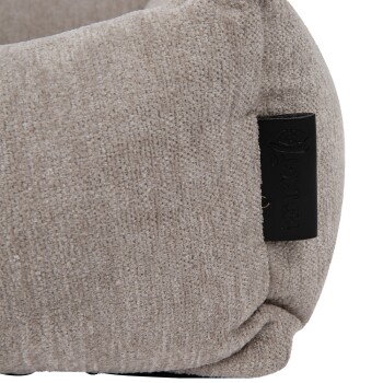 Nahaufnahme eines weichen, beigen Haustierbettes mit strukturiertem Stoff und einem schwarzen Lederetikett mit dem Markennamen 'Lersha'.