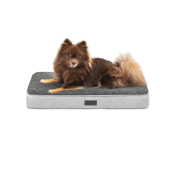 Ein flauschiger brauner Pomeranian-Hund, der auf einem plüschigen, grauen Haustierbett mit einem Diamantmuster ruht, das ein kleines "lionto"-Logo trägt.