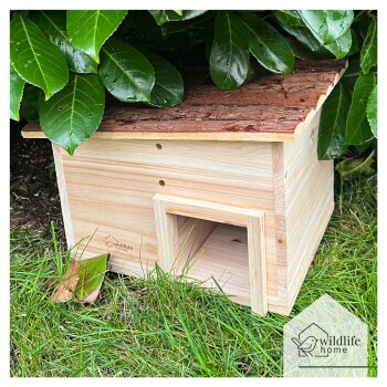 Holz-Wildtierschutz mit einem mit Rinde bedeckten Dach, eingebettet zwischen grünen Blättern, mit einem kleinen Eingang und dem Logo 'wildlife home.'