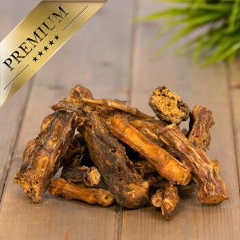 Ein Paar Hände hält verschiedene Hundekauartikel, mit einem Abzeichen mit der Aufschrift 'Beste Qualität' und '15 Jahre' auf Deutsch.