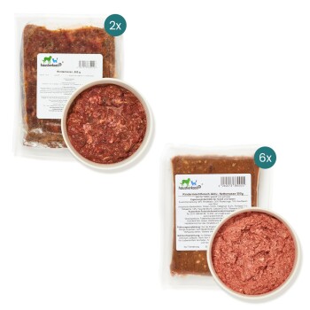 Rohes Rindfleisch-Hundefutter in zwei vakuumverpackten Beuteln und einer Schüssel, beschriftet mit "Rindermischfleisch Aktiv, Nettomasse 500g."