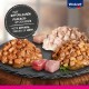 Haustierfutter mit natürlichen Fleischstücken, präsentiert auf einem Schieferteller mit drei verschiedenen Geschmacksrichtungen und Stücken rohen Fleisches.