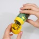 Eine Person, die grüne Haustierergänzungstabletten aus einer gelben Flasche in einen gelben Deckel gießt, wobei das Etikett der Flasche teilweise sichtbar ist.
