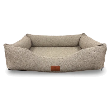 Rechteckiges beiges Tweed-Hundebett mit erhöhten Seitenkissen und abgesenkter Vorderseite, braunes Lederetikett mit der Aufschrift PETLIVING.