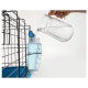 Une personne verse de l'eau d'une carafe transparente dans une bouteille d'eau bleue attachée à une cage pour animaux, démontrant une solution d'hydratation pour animaux.