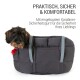 Ein kleiner Hund schaut aus einer gepolsterten Tragetasche mit grauen Riemen. Der Text oben sagt "Praktisch, sicher & komfortabel." Unten: "Mit Karabiner-Sicherheitsgurt."