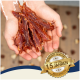Hände halten Streifen von Haustier-Jerky mit einem Abzeichen, das 'Beste Qualität' und '15 Jahre' auf Deutsch angibt.