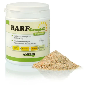 Contenant de mélange d'herbes BARF Complex pour animaux de compagnie, avec un tas du mélange à côté ; étiqueté comme supplément vitaminique et minéral.