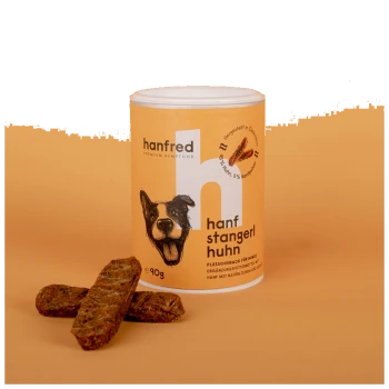 Ein Behälter mit "hanfred" Premium Hanf-Futter für Hunde, beschriftet "hanf stangerl huhn," mit drei braunen Hundeleckerlis davor.