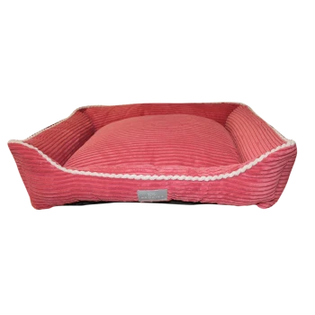 A plush, pink pet bed with a ribbed texture and white braided trim, featuring a small label that reads "Beddies."