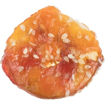 A close-up of a chewy, round pet treat with a glossy, orange-red surface and sprinkled with white sesame seeds.