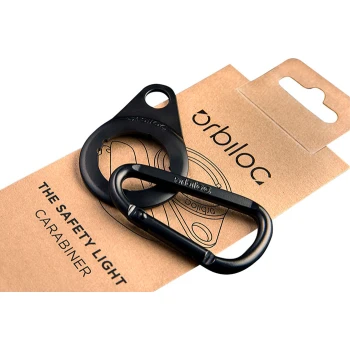 Schwarzer Sicherheitslicht-Karabiner und Ring auf einer braunen Kartonverpackung, beschriftet 'orbiloc' und 'DER SICHERHEITSLICHT-KARABINER.'