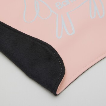 Eine Nahaufnahme einer Haustierdecke mit einer pinken Oberseite und einer silbernen Umrisszeichnung eines Hundes sowie dem Wort "Bark" darüber, mit schwarzem Fleece eingefasst.