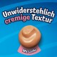 Kleckser cremigen Tierfutters mit Lachs auf blauem Hintergrund mit dem Text 'Unwiderstehlich cremige Textur' und 'Mit Lachs'.