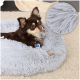 Ein entspannter brauner Chihuahua ruht auf einem flauschigen grauen Haustierbett, mit einer Nahaufnahme der weichen Stofftextur in der Ecke.