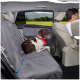 Ein brauner und weißer Hund mit einem roten Halstuch sitzt bequem auf einem grauen Haustiersitzbezug auf dem Rücksitz eines Autos, mit einer malerischen Aussicht draußen.