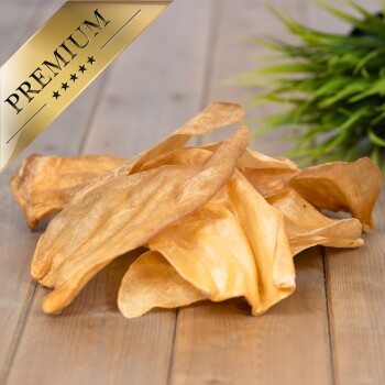 Premium-Hundeleckerlis, die auf einer Holzoberfläche präsentiert werden, mit einem goldenen Etikett mit fünf Sternen.